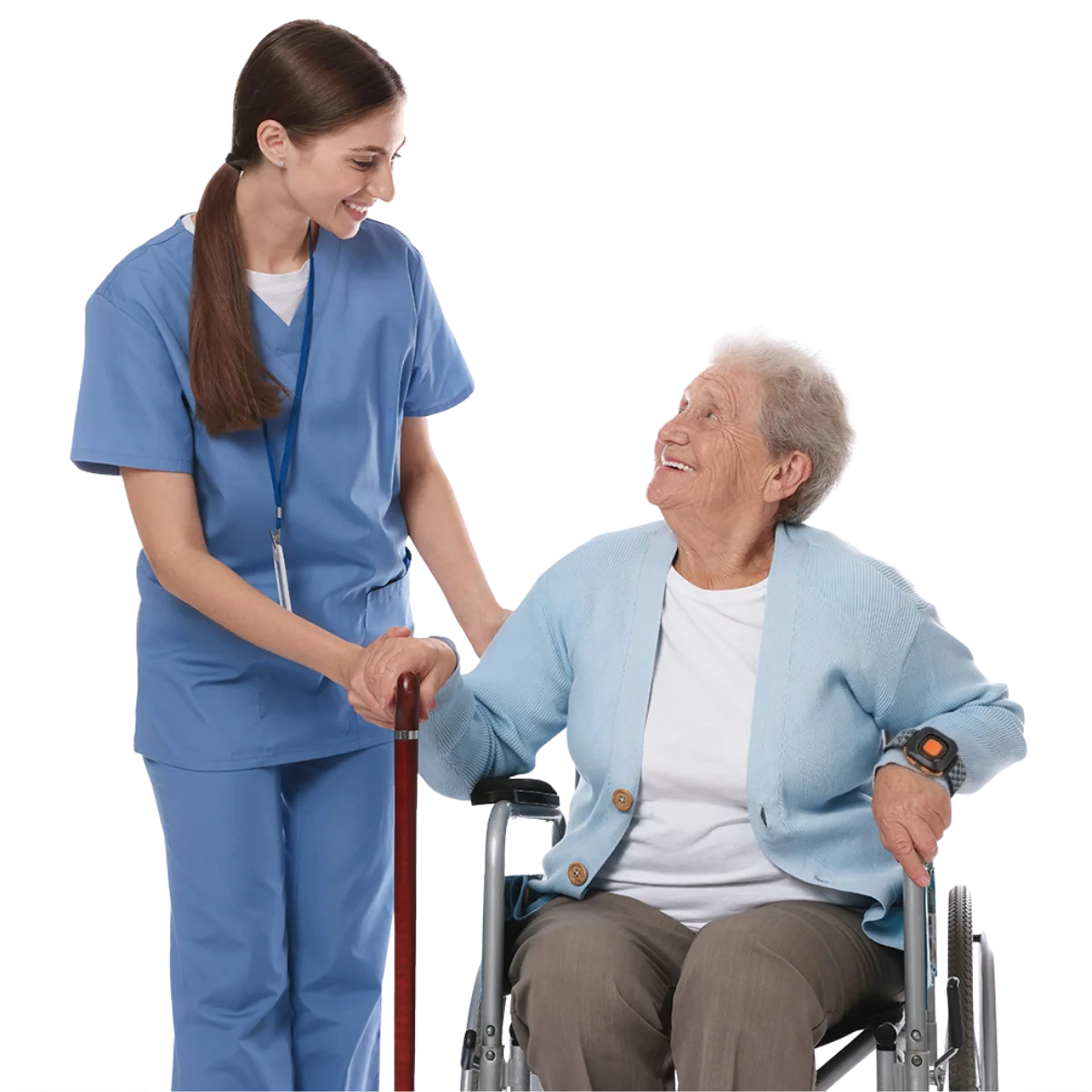 A nurse in blue scrubs smiling and holding hands with an elderly patient in a wheelchair.