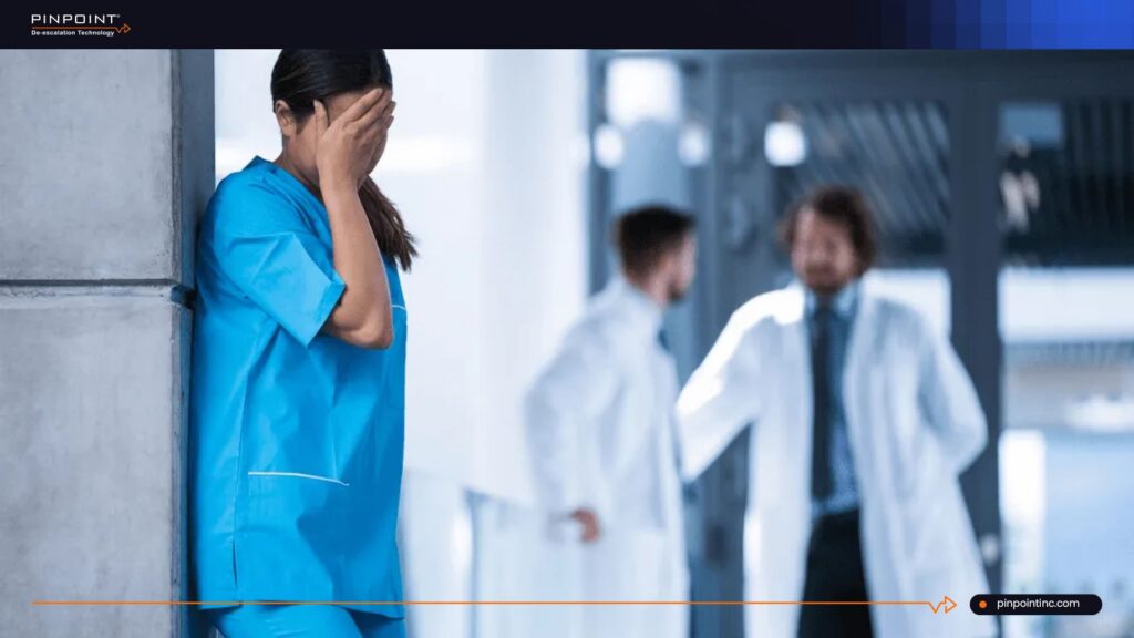 Distressed nurse in hospital with doctors in background highlighting workplace violence concerns