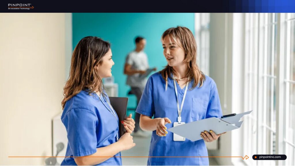 Healthcare staff discussing non-tracking nurse safety system in hospital corridor